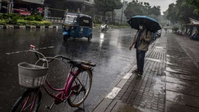 Ilustrasi warga berjalan menggunakan payung saat hujan di Jakarta.